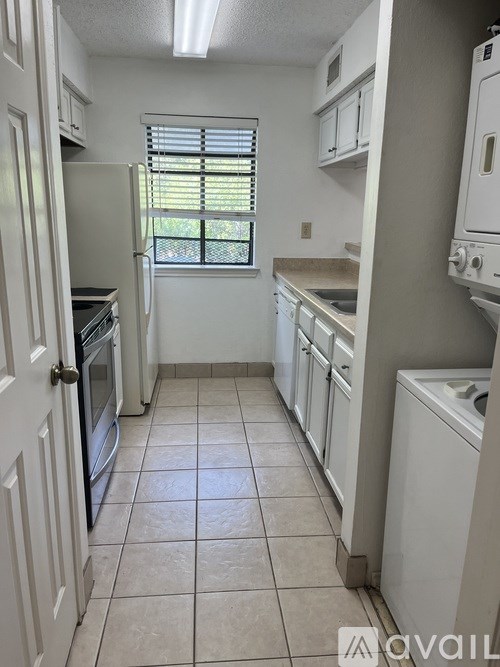 A kitchen with white appliances and a tiled floor.