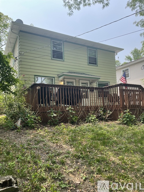 A green house with a wooden fence in front of it.