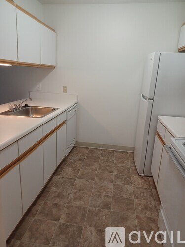 A kitchen with white cabinets and a white fridge.