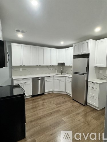 A kitchen with white cabinets and a wooden floor.