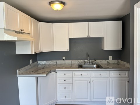 A kitchen with white cabinets and a marble countertop.