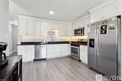 A kitchen with white cabinets and a stainless steel refrigerator.