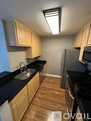 A kitchen with wooden cabinets and black countertops.