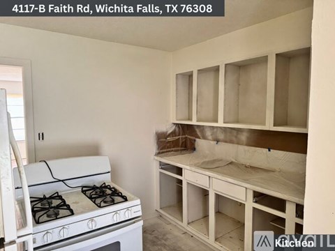 A kitchen under construction with a white stove and empty cabinets.
