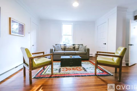 A living room with a couch, two chairs and a rug.