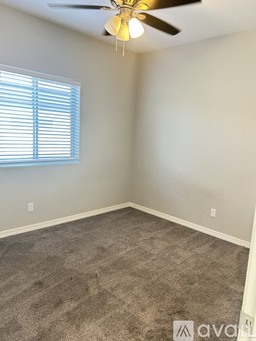 A room with a ceiling fan and a window with blinds.