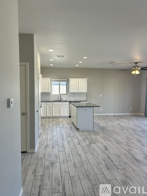 A spacious kitchen with a wooden floor and a ceiling fan.