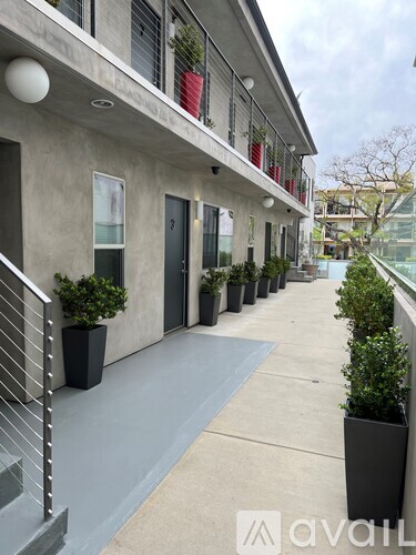 A building with a balcony and potted plants on the ground.