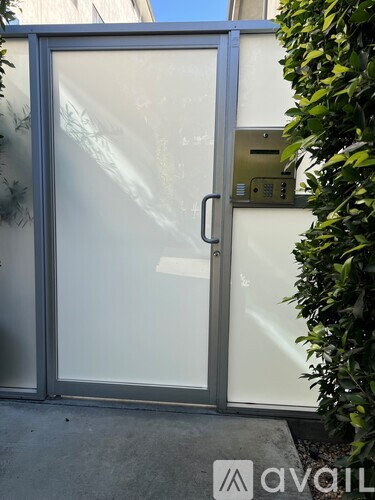 A glass door with a handle and a keypad on the wall.