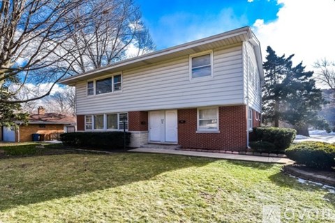 A two-story house with a white garage door and a brick facade.