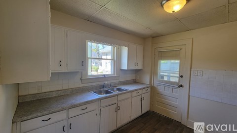 A kitchen with white cabinets and a window above the sink.
