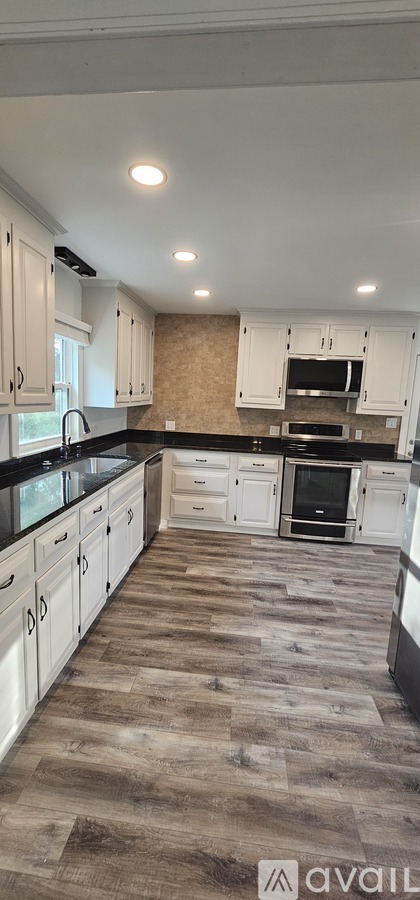 A kitchen with white cabinets and a wooden floor.