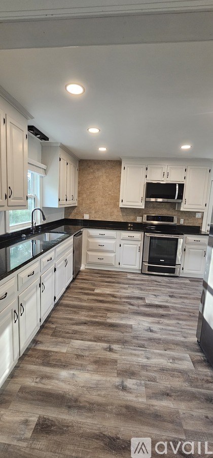 A kitchen with white cabinets and a wooden floor.