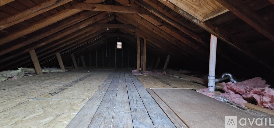 A spacious attic with wooden floors and exposed beams.