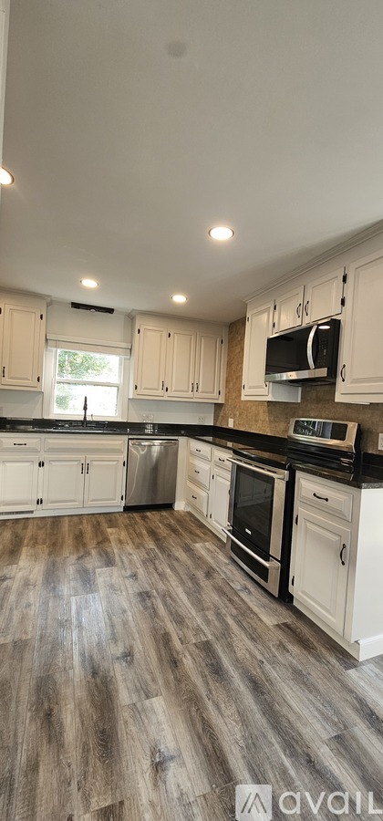 A kitchen with white cabinets and a wooden floor.