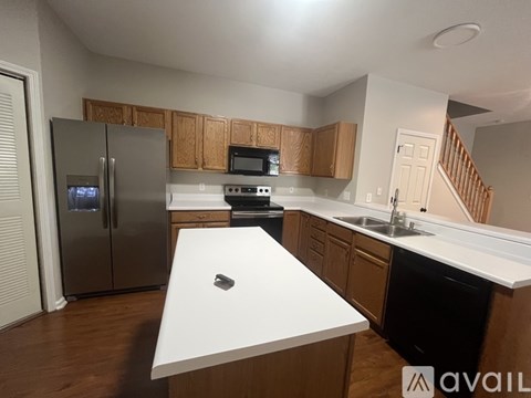 A kitchen with a refrigerator, oven, microwave, and sink.