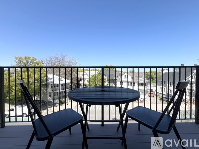 A balcony with a table and two chairs overlooking a street.