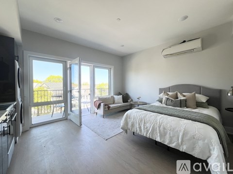 A bedroom with a large bed and sliding glass doors leading to a balcony.