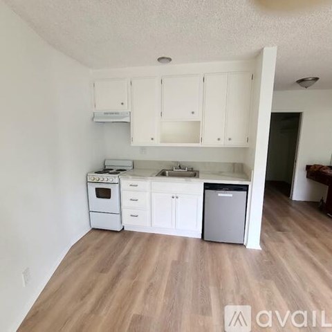 A kitchen with white cabinets and a wooden floor.
