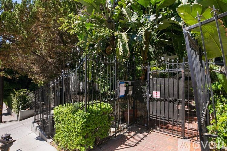 A black metal fence with a gate and a sign on it.