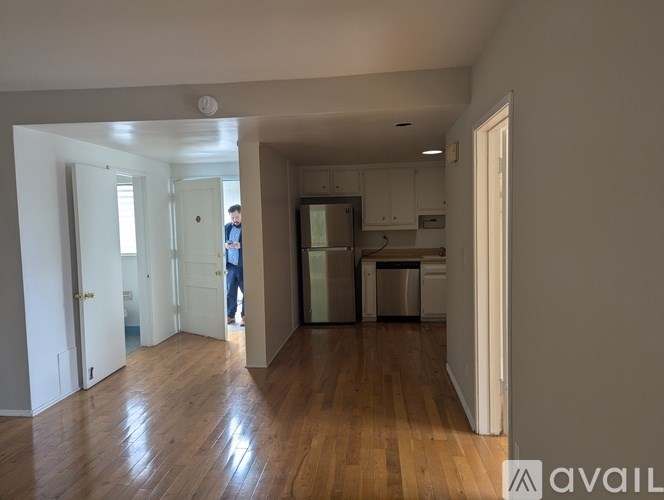 A man is standing in a room with wooden floors and white walls.