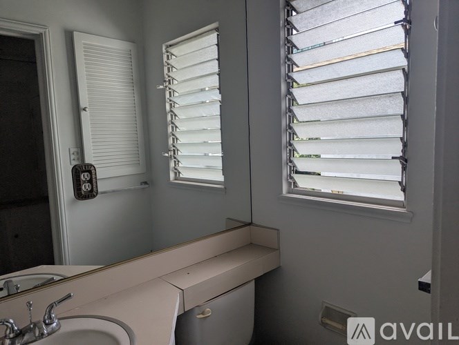 A bathroom with a sink, mirror, and window with blinds.