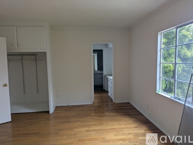 A room with wooden floors and white walls, with a window on the right side.