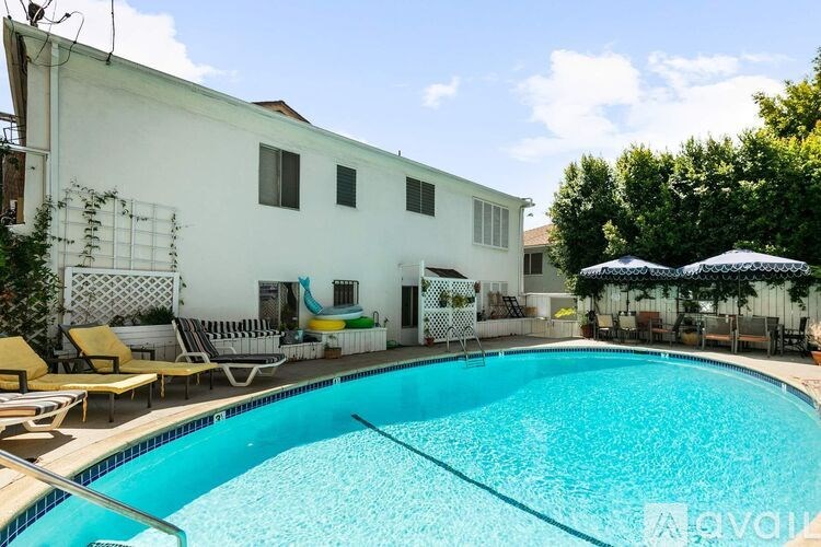 A swimming pool in front of a white building with a blue sky in the background.