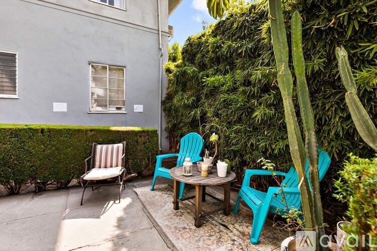 A patio with a table and chairs surrounded by greenery.