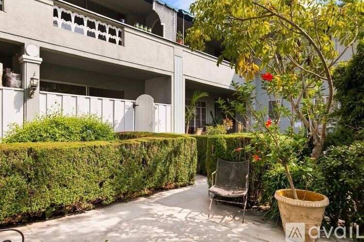 A patio with a chair and a potted plant is in front of a building.