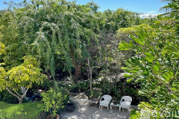 A backyard with a patio, chairs, and trees.