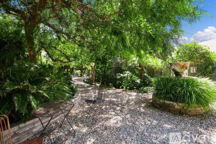 A backyard with a gravel area, a tree, and a small table.