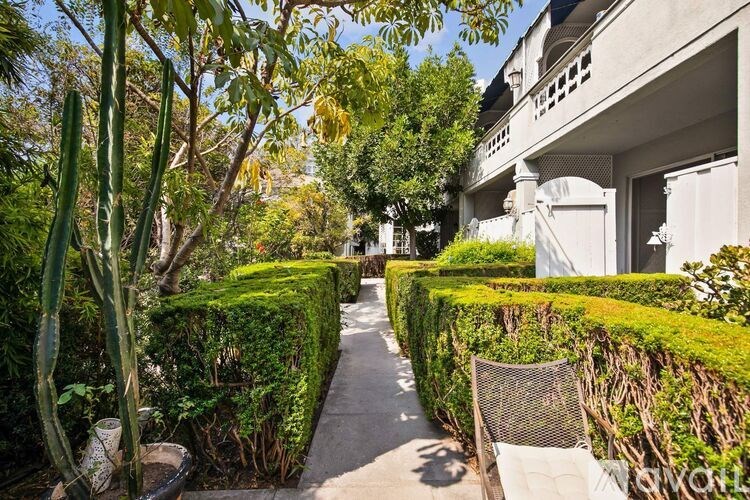 A pathway leads through a garden with a white building on the right.