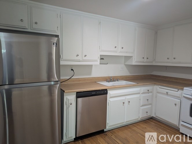 A kitchen with white cabinets and a stainless steel refrigerator.