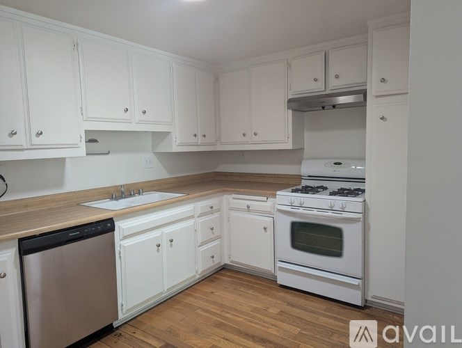 A kitchen with white cabinets and a wooden counter top.
