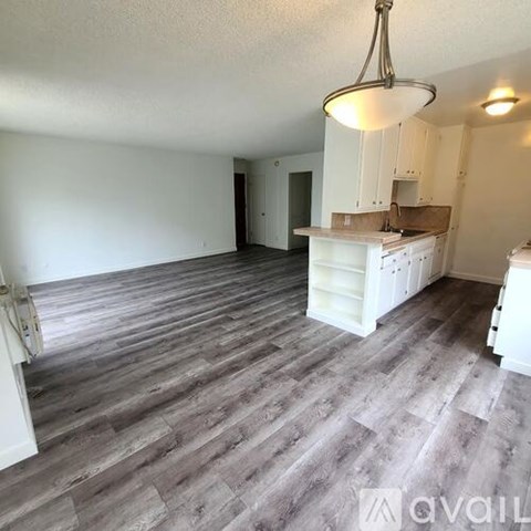 A kitchen with white cabinets and a grey floor.