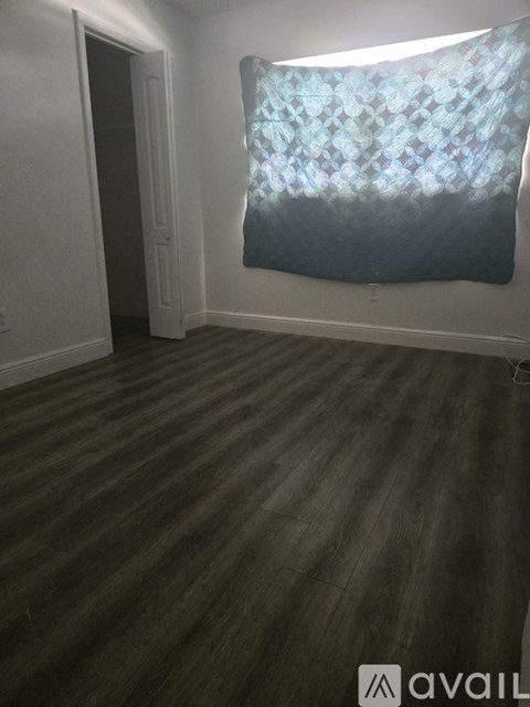 A messy bedroom with a bed, desk, and a TV.