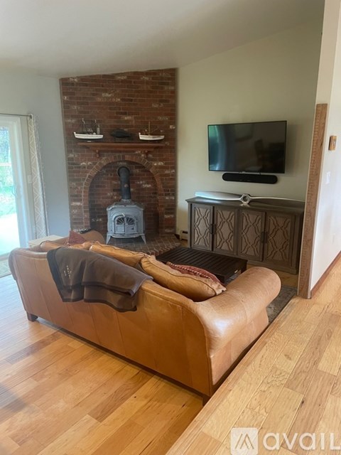 A living room with a leather couch and a brick fireplace.