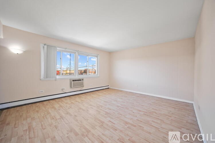 A room with wooden flooring and a window overlooking a building.