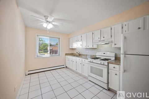 A kitchen with white appliances and cabinets is available for rent.