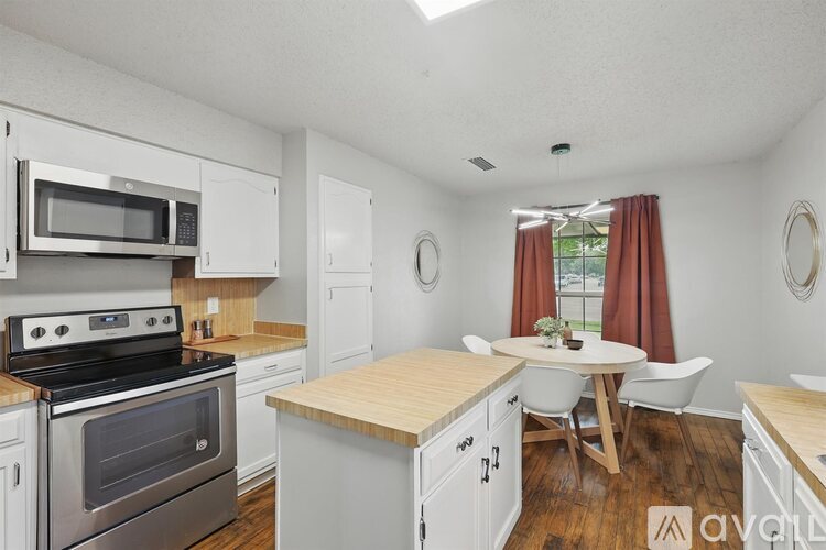 A kitchen with white cabinets and a wooden island.