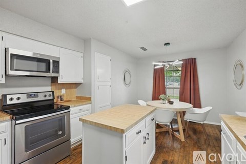 A kitchen with white cabinets and a wooden island.