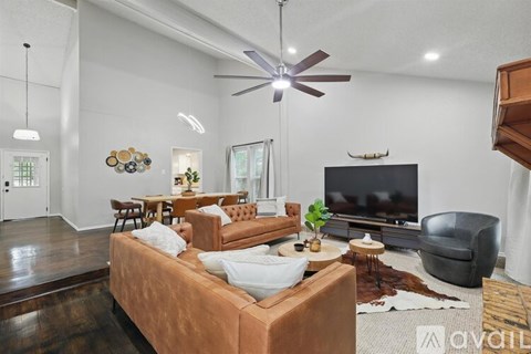 A living room with a brown couch and a television mounted on the wall.