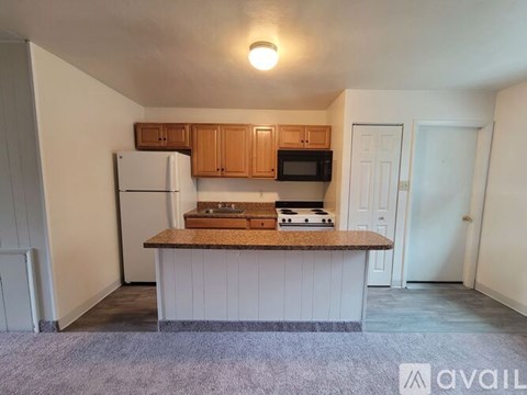 A kitchen with a refrigerator, microwave, and stove top oven.