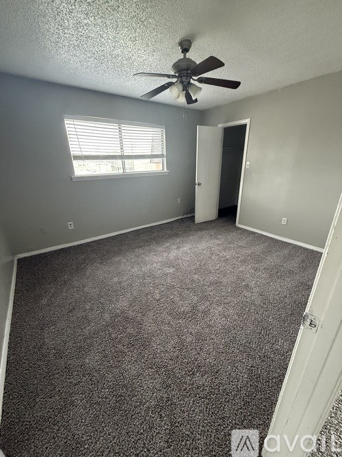 A room with a ceiling fan and carpeted floor.