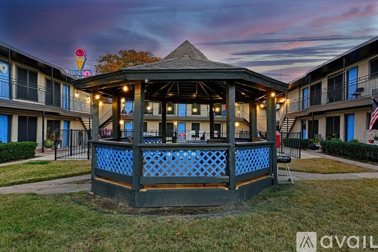 A gazebo-style pavilion is surrounded by apartment buildings and has a blue lattice fence around it.