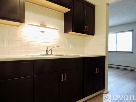 A kitchen with dark brown cabinets and a white subway tile backsplash.