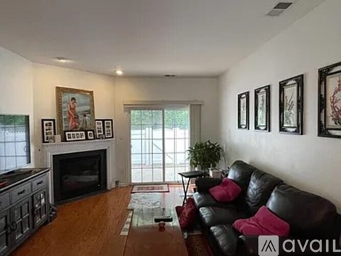 A living room with a black leather couch and a fireplace.