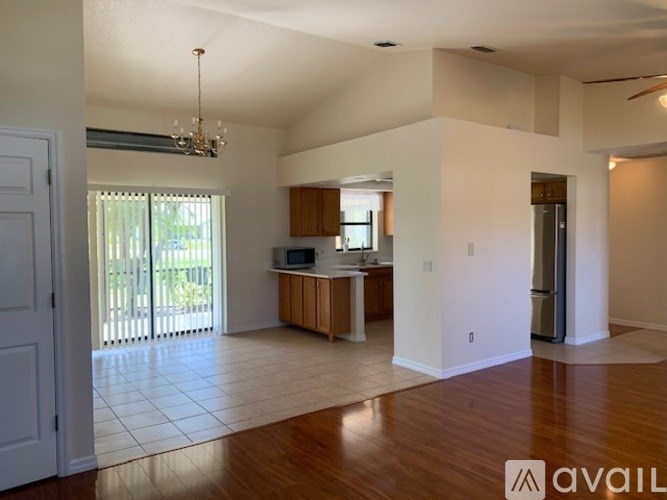 A spacious living room with a kitchen in the background.