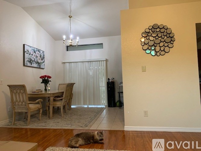 A dining room with a table set for two and a cat lying on the floor.